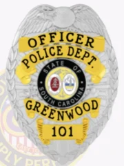 Silver metal badge with an eagle perched at the top, customized for Greenwood Police Officer, displaying black lettering on curved yellow scrolls stating "OFFICER," "POLICE DEPT.," and "GREENWOOD," with the number "101" on a yellow plate at the bottom, encircling the vibrant South Carolina state emblem, secured by a safety pin.