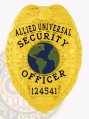 Detailed gold-colored badge adorned with an eagle motif, reading "ALLIED UNIVERSAL SECURITY OFFICER" above a globe illustration. The badge is equipped with a safety pin attachment, making it practical for wear. This custom metal badge in gold color with safety pin attachment exemplifies excellence in security service.