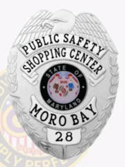 A striking custom metal badge in silver color with a safety pin attachment highlights the titles "PUBLIC SAFETY" and "SHOPPING CENTER." The design includes a colorful depiction of the Maryland state seal at the center, framed by elegant silver accents.