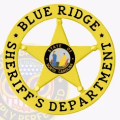 A close up of a custom metal badge in gold color with safety pin attachment, designed in the shape of a star. The badge features "blue ridge" and "sheriff's department" in bold black letters around the edge. In the center, it displays the emblem for the state of north carolina, showcasing a colorful depiction of its emblem. This badge presents a vibrant and authoritative look, ideal for law enforcement professionals.