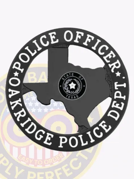 Black metal badge shaped like Texas for Oakridge Police Officer, displaying the Texas state seal inside the black state outline, encircled by a black ring with white lettering “Police Officer” and “Oakridge Police Dept,” secured by a safety pin fastener.