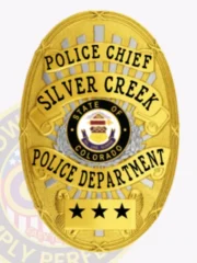 Gold custom oval metal badge for Silver Creek Police Chief displaying a central Colorado state seal, accented by gold banners with black text for "POLICE CHIEF," "SILVER CREEK," and "POLICE DEPARTMENT," and a bottom panel featuring three black stars, fastened with a safety pin.