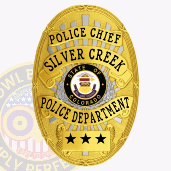 Oval gold metal badge designed for Silver Creek Police Chief, showcasing the Colorado state seal at the center, framed by gold banners with bold black lettering "POLICE CHIEF," "SILVER CREEK," and "POLICE DEPARTMENT," and three black stars on a gold plate at the bottom, attached via safety pin.