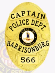 Oval-shaped custom gold metal badge for Harrisonburg Police Captain showing a raised Virginia state seal in the center, surrounded by gold banners with black text "CAPTAIN," "POLICE DEPT.," "HARRISONBURG," and badge number "566," held by a safety pin.