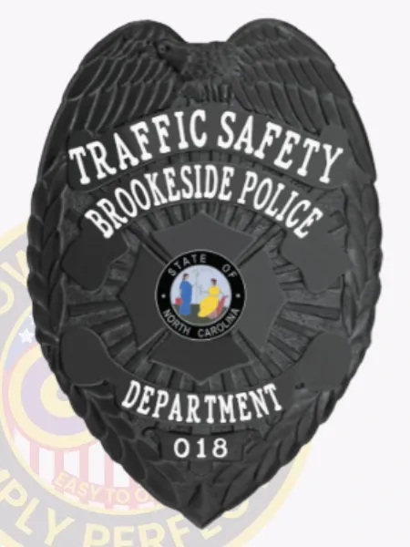 This striking image showcases a custom metal badge in black, marked with the title "TRAFFIC SAFETY" and "BROOKESIDE POLICE." The badge includes the state seal of North Carolina and identifies as part of the department with the number 018. The safety pin attachment is clearly visible, ensuring easy wear for officers.