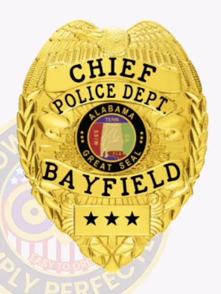 A gold custom metal badge highlighted by an elegant design, prominently featuring the title "CHIEF." The badge includes text for "POLICE DEPT. BAYFIELD," showcases the Alabama state seal in its center, and is designed with a safety pin attachment for convenience.