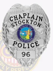 Featuring a custom metal badge in silver color with a safety pin attachment, this badge highlights "CHAPLAIN," "STOCKTON," and "POLICE." The central circular design showcases the California state seal, enhanced by the shiny silver finish that represents service and dedication.