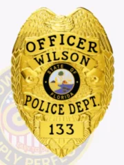 Wilson Police custom gold metal officer badge with an eagle crest, prominent black text "OFFICER WILSON POLICE DEPT." around the Florida state emblem, and a bottom number "133," equipped with a safety pin for attachment.