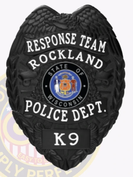 A sleek custom metal badge in black, shaped like a shield with detailed engravings. The badge prominently displays "RESPONSE TEAM ROCKLAND" at the top in bold white lettering. In the center, the state seal of Wisconsin is featured within a circular design, surrounded by a decorative black border. Below this, "POLICE DEPT." is inscribed, and the badge includes the designation "K9" at the bottom in a white panel. The matte finish of this custom metal badge in black enhances its professional appearance, symbolizing authority and dedication in law enforcement.