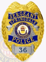 A custom metal badge in gold with silver panels featuring the words "SERGEANT" and "SPRINGDALE" at the top. The badge displays the emblem of Colorado's state seal in the center, surrounded by decorative silver laurel leaves. The word "POLICE" is prominently displayed in blue at the bottom, with the number "36" in a silver panel below it. The badge has a textured gold background and ornate wing-shaped designs at the top.