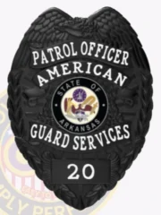 Detailed look at a custom metal badge in black color with safety pin attachment, featuring a shield design. The top inscription states "PATROL OFFICER," while "AMERICAN" is highlighted beneath it. The central area showcases the state seal of Arkansas, and "20" is displayed on a black panel at the bottom, reinforcing its official capacity.