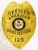 Custom metal badge in gold color with safety pin attachment, designed in a shield shape. The badge prominently displays "OFFICER AMERICAN" at the top, followed by "GUARD SERVICES" beneath. The center features the state seal of Arkansas, surrounded by detailed engravings. At the bottom, the number "125" is clearly visible, indicating its official designation.