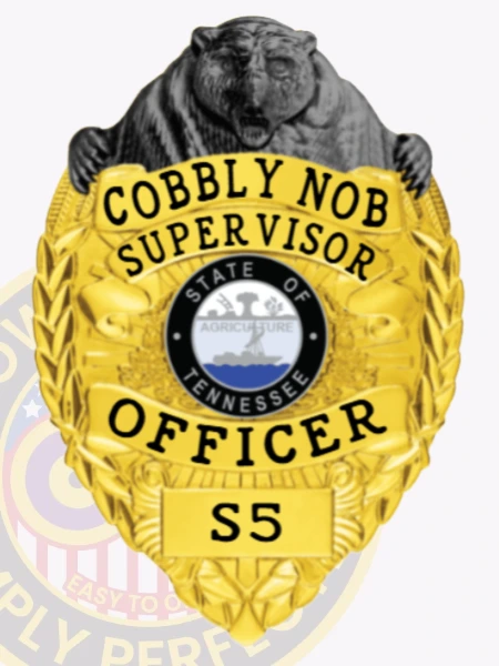 A custom metal badge in gold with black bear top and safety pin attachment, prominently displaying "Cobbly Nob Supervisor" and "OFFICER." The badge features the state emblem of Tennessee, surrounded by intricate designs that enhance its authoritative appearance.