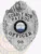 A detailed view of a custom silver badge with safety pin attachment, presenting "Cobbly Nob Patrol" and "OFFICER" in bold letters. The badge features a bear motif at the top and intricate designs, emphasizing its official purpose and elegant appearance.