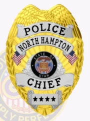 A striking custom metal badge gold with silver panels, shaped like a shield and featuring intricate detailing. The badge prominently displays "POLICE" at the top, followed by "NORTH HAMPTON" in bold black letters on a silver panel. In the center, the state seal of Utah is encircled by a decorative silver border, showcasing its design. Below the seal, the word "CHIEF" is written in bold letters, and four stars are displayed at the bottom. The combination of the shiny gold finish and silver accents of this custom metal badge gold with silver panels emphasizes its authority and prestige in law enforcement.