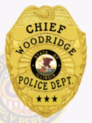 Woodridge Police Chief’s custom gold metal badge showing a detailed gold eagle crest on top, bold black letters spelling "CHIEF WOODRIDGE POLICE DEPT.," Illinois state seal in the center and three black stars on a gold plate below, attached with a safety pin.