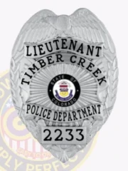 A distinctive custom metal badge in glossy silver showcases the title "LIEUTENANT" and "TIMBER CREEK." The center features the emblem of Colorado, encircled by "POLICE DEPARTMENT" and identification number "2233." It is equipped with a safety pin attachment for convenient application on various clothing items.