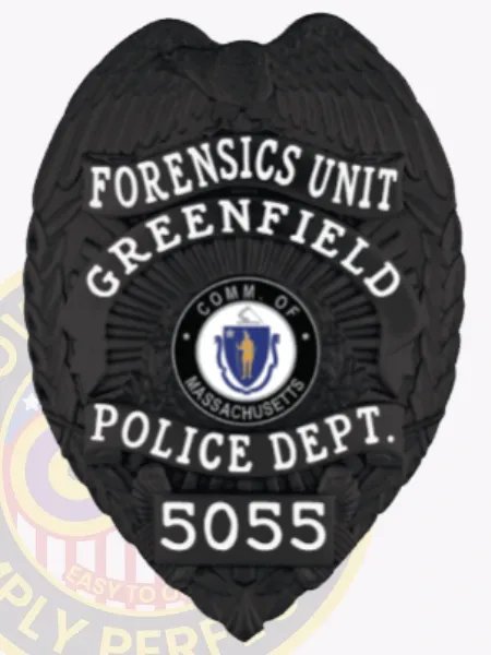 Greenfield Police Forensics Unit custom black metal badge, showing a detailed eagle with wings spread at the top, bold white lettering around the Massachusetts emblem, labeled “FORENSICS UNIT” and numbered “5055,” attached with a safety pin.