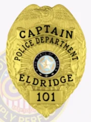Eldridge Police Captain gold metal badge with eagle figure atop, clear black text including "CAPTAIN POLICE DEPARTMENT ELDRIDGE," Texas state seal centered, number "101" below, and a safety pin attachment.