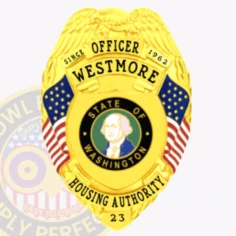 A closeup of a custom metal badge in gold featuring the title “officer westmore” prominently displayed at the top. The badge is adorned with an eagle emblem and features american flags on either side. In the center, there is a circular seal depicting george washington, representing the “state of washington. ” the words “housing authority” are clearly visible below the seal, along with the badge number “23. ” the shiny gold finish gives this official badge a prestigious and authoritative appearance.