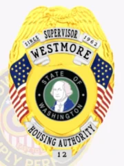 A custom metal badge in gold with silver panels featuring the title “SUPERVISOR WESTMORE” prominently displayed at the top. The badge is designed with an eagle emblem at the top and includes American flags on either side. In the center, a circular seal depicts George Washington, representing the “STATE OF WASHINGTON.” The words “HOUSING AUTHORITY” are clearly visible below the seal, along with the badge number “12.” The combination of gold and silver panels gives this official badge a striking and distinguished appearance.