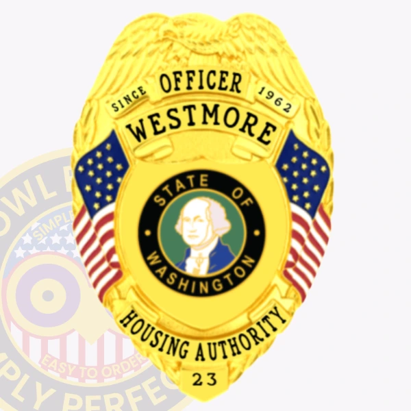 A closeup of a custom metal badge in gold featuring the title “OFFICER WESTMORE” prominently displayed at the top. The badge is adorned with an eagle emblem and features American flags on either side. In the center, there is a circular seal depicting George Washington, representing the “STATE OF WASHINGTON.” The words “HOUSING AUTHORITY” are clearly visible below the seal, along with the badge number “23.” The shiny gold finish gives this official badge a prestigious and authoritative appearance.
