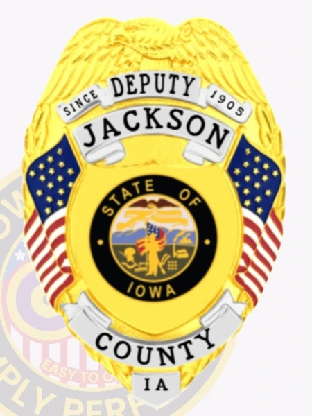 A custom metal badge in gold with silver panels showcasing the title "DEPUTY" at the top, followed by the name "JACKSON" and "SINCE 1905." The center features a circular emblem representing the state of Iowa, adorned with decorative blue panels and American flags on either side. Below the emblem, the badge reads "COUNTY IA." The polished gold finish and contrasting silver panels enhance the badge's official look, emphasizing its significance and authority within law enforcement.