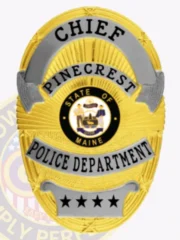 Custom police metal badge in gold oval shape for Pinecrest chief, displaying a sunburst pattern in gold with silver scrolls containing black lettering reading "CHIEF," "PINECREST," and "POLICE DEPARTMENT," topped by a silver plate with four black stars and centered around the Maine state seal.