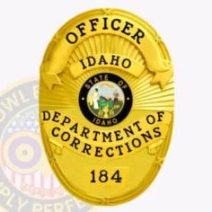 Close up of a custom metal badge in gold with silver panels, featuring a velcro attachment, specifically designed for an officer in the idaho department of corrections. The badge highlights the state emblem at its center, surrounded by the words "officer" at the top and "department of corrections" at the bottom. The design is elegant, with a rich gold finish that accentuates its authority and professionalism, making it easily recognizable.