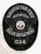 This impressive custom metal badge in black highlights a unique oval shape with detailed engraving. The top section reads "NARCOTICS TASK FORCE" in prominent white lettering. The center features the Greenfield Police Department insignia, framed by "STATE OF KENTUCKY." At the bottom, "POLICE DEPARTMENT" and "024" are clearly displayed. A durable safety pin attachment allows for easy and secure wear of the badge.