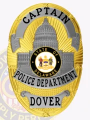 Custom Dover Police Captain badge in gold and silver tones with a prominent Capitol building and Delaware seal in the middle, marked with "CAPTAIN" at the top, "POLICE DEPARTMENT" across the center, and "DOVER" on a banner below, attached via safety pin.