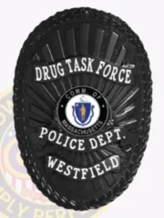 Black oval custom metal badge for Westfield police drug task force with safety pin back, displaying embossed laurel leaves around the border, white uppercase text on black banners for "DRUG TASK FORCE," "POLICE DEPT.," and "WESTFIELD," featuring the official Massachusetts state seal.