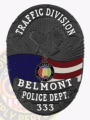 Oval black metal badge designed for Belmont Police Traffic Division, showing an eagle emblem above the American flag and Alabama state seal, with bold white lettering "TRAFFIC DIVISION," "BELMONT," "POLICE DEPT.," and "333," fastened by a safety pin.