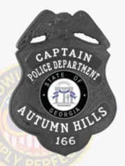 Autumn Hills police captain’s custom black metal badge shaped like a shield with an eagle perched above, white embossed text highlighting rank and department, centered by the State of Georgia seal, and finished with a safety pin fastener.