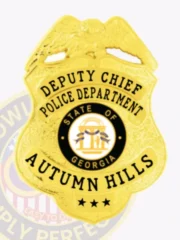 Detailed gold metal badge featuring an eagle on top of a textured shield for the Autumn Hills police deputy chief, including the State of Georgia seal and prominent black text, secured with a safety pin backing.