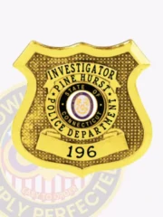Detailed custom gold shield metal badge for Pine Hurst police the investigator with safety pin attachment, featuring a reflective gold badge shaped like a shield with textured background dots, black text for "INVESTIGATOR," "PINE HURST POLICE DEPARTMENT" around the state seal, and "196" on a gold banner beneath.