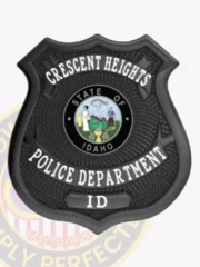 Crescent Heights Police custom black metal shield badge with bold white lettering on a black textured surface, showcasing the State of Idaho seal in the middle, designed with a safety pin attachment for secure fastening.