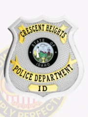 Silver shield-shaped custom metal badge for Crescent Heights Police Department, displaying black text on shiny gold panels over a textured silver base, a colorful Idaho state seal in the middle, and equipped with a safety pin attachment.
