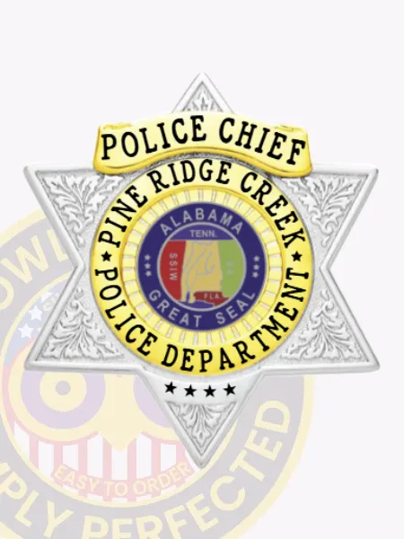 Six-point star silver metal badge with gold panels for Pine Ridge Creek Police Chief, featuring elaborate floral engraving on the silver star points, a prominent gold banner inscribed with "Police Chief," and a central gold circle surrounding the Alabama Great Seal and department text, accompanied by four black stars at the tip; fastened by safety pin.