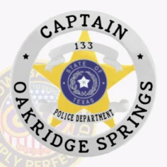 Custom gold 5 point star metal badge for oakridge springs police captain, set within a shiny silver circular banner that reads "captain" at the top and "oakridge springs" along the bottom, featuring a blue texas state seal in the center and a safety pin attachment.