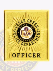Gold square flex badge for Cedar Creek police officer with a raised starburst pattern, central black and gold Arkansas state seal enclosed by "CEDAR CREEK POLICE DEPARTMENT" text in black, and a gold panel at the bottom with "OFFICER" in black font, designed with velcro attachment.