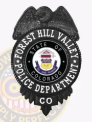 Custom black metal badge for Forest Hill Valley police, showing an eagle embossed at the top, bold white text "FOREST HILL VALLEY POLICE DEPARTMENT" encircling the multi-colored Colorado state seal, and "CO" displayed on a black lower panel, equipped with a safety pin attachment.