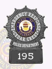 Circle starburst black metal badge on square base for Cedar Crest police emergency response unit, featuring a black sunburst design, white text reading "Emergency Response" and "Cedar Crest" around the Colorado state seal in the center, a black banner with "Police Department," and a base labeled "195," attached with safety pin.