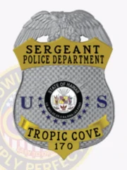 Detailed silver metal shield badge with an eagle perched atop for Tropic Cove police sergeant, featuring gold panels with bold black lettering, the State of Hawaii seal in the center and blue letters “U” and “S,” attached by a safety pin.