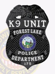 Metal badge in black with eagle crest for Forest Lake police K9 Unit, showing “K9 UNIT FOREST LAKE POLICE DEPARTMENT” in white letters, centered by the official Idaho state seal, and secured with a safety pin.