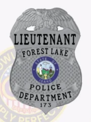 Custom silver eagle top shield metal badge for Forest Lake police lieutenant, featuring bold black text “LIEUTENANT FOREST LAKE POLICE DEPARTMENT” across silver banners, with the colorful State of Idaho seal in the center and badge number 173, attached with a safety pin.
