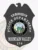Black metal police badge shaped like a shield topped with an eagle, labeled "K9 DIVISION" and "POLICE DEPARTMENT" in white letters, showing the colorful Idaho state seal in the middle, with "MOUNTAIN VALLEY" and badge number "178" below, secured by a safety pin on the back.