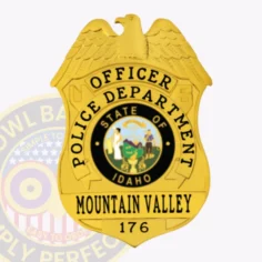Custom metal badge for mountain valley police officer in bright gold, showing an eagle perched atop a shield, black lettering reading "officer" and "police department," central idaho state seal in color, and "mountain valley 176" engraved below, attached using a safety pin.