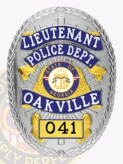 This eye-catching custom metal badge in silver with reverse enamel blue accents and with safety pin attachment features "LIEUTENANT" boldly at the top in white letters against the polished silver backdrop. Below, "POLICE DEPT." stands out prominently, with "OAKVILLE" showcased in vibrant blue. The central design includes the state seal of Georgia, and the number "041" is featured within a contrasting box at the base, enhancing its official appearance.