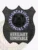 Black shield-shaped metal badge for Ontario Provincial Police Auxiliary Constable, showing the official provincial coat of arms inside a blue circle, with “Auxiliary Constable” text in white on a black plaque beneath, fastened by safety pin.